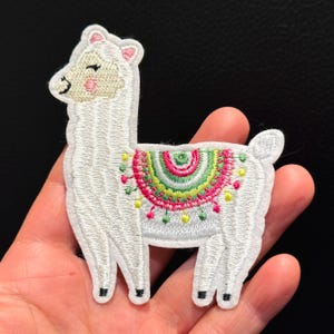 Könnte beinhalten: Weißer gestickter Lama-Aufnäher mit einem bunten Regenbogenmuster auf dem Rücken.