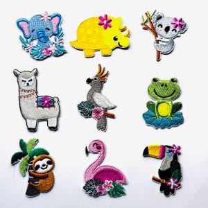 May include: A selection of embroidered patches showcasing diverse animals. Designs include an elephant, dinosaur, koala, llama, parrot, frog, sloth, flamingo, and toucan. Each patch is decorated with floral details and bright colours.