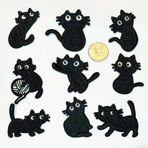 May include: Set of ten black embroidered iron-on patches featuring cute cartoon cats in various poses. The patches are approximately 1.5 inches in size.