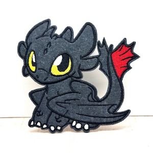 May include: A dark grey dragon patch with yellow eyes and a red tail fin. The patch is made of felt and has white stitching. The dragon is in a sitting position.