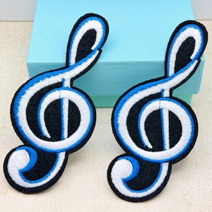 May include: Two embroidered treble clef patches. Each patch has a black base with white and blue stitching outlining the musical symbol. Ideal for sewing or ironing onto fabric, these patches are perfect for music enthusiasts and crafters.