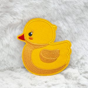 Può includere: Toppa ricamata a forma di anatra gialla con becco rosso e piccolo occhio nero. L'anatra presenta un design a punto dettagliato, adatta per abbigliamento o accessori.