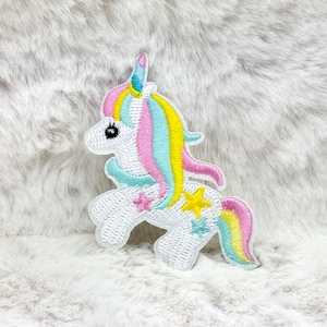 May include: Embroidered unicorn patch with a white body, a blue and yellow horn, and a flowing mane of pink, blue, and yellow. The patch features star accents in pink, yellow, and blue. The patch is designed for clothing or accessories.