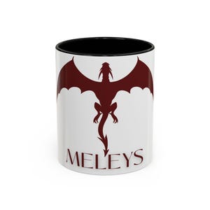 May include: White ceramic mug with a black rim. The mug features a red silhouette of a dragon with wings spread and the text "MELEYS" printed below.