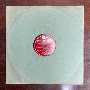 May include: A vintage vinyl record by Frank Sinatra, featuring the song "Mam'selle." The record label is red with white text and the Columbia Records logo. The record is housed in a light green paper sleeve.