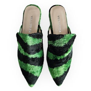 May include: A pair of green and black zebra-striped velvet slippers with pointed toes. The slippers have the brand name "VELVETICA" written on the inside.