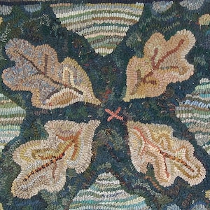 Puede incluir: Primer plano de una alfombra hecha a mano con un diseño de cuatro hojas de roble en tonos marrones, beige y crema sobre un fondo verde oscuro.
