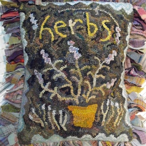 May include: A handmade rug with a frayed edge, featuring a potted plant with the word "herbs" embroidered in yellow yarn.
