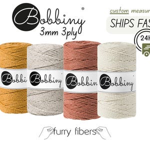May include: Four spools of 3mm 3-ply cotton rope in different colors: mustard yellow, light gray, terracotta, and natural white. The spools are labeled "Bobbiny" and "Furry Fibers".