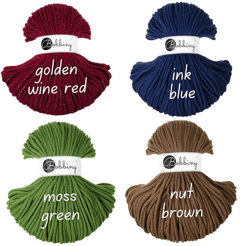 May include: Four bundles of Bobbiny macrame cord in golden wine red, ink blue, moss green, and nut brown. Each bundle is labeled with its color name. The cords are tightly wound, showcasing their texture and color variations, ideal for crafting projects.