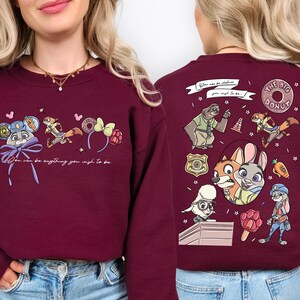 a woman wearing a burgundy sweater with various cartoon characters and designs on the back.