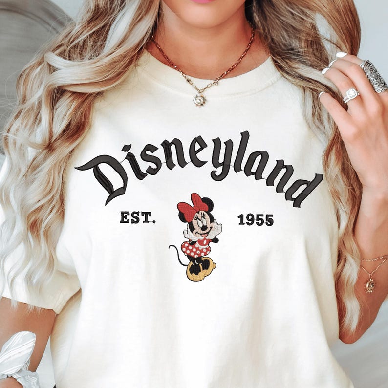 A woman wearing a white t-shirt with the text "Disneyland EST. 1955" and an image of Minnie Mouse, a character from the Disney theme park.