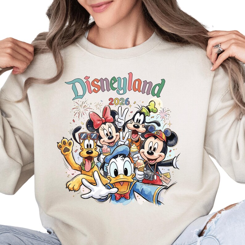 A woman wearing a white sweatshirt with a colorful graphic of Disney characters from the theme park.