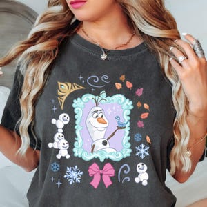 A woman wearing a black t-shirt with a graphic design featuring characters from the Disney movie Frozen.