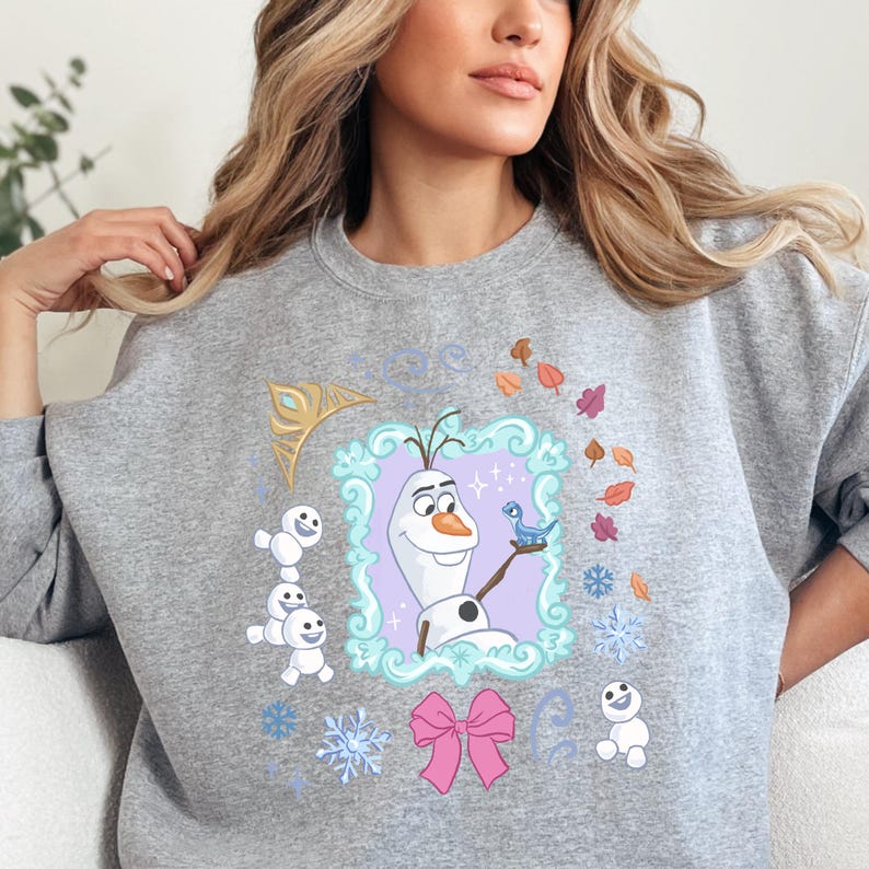 A woman wearing a gray sweatshirt with a graphic design featuring characters from the Disney movie Frozen.