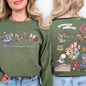 A woman wearing a green sweater with a cartoon character design on the front and the back featuring various cartoon characters and text.
