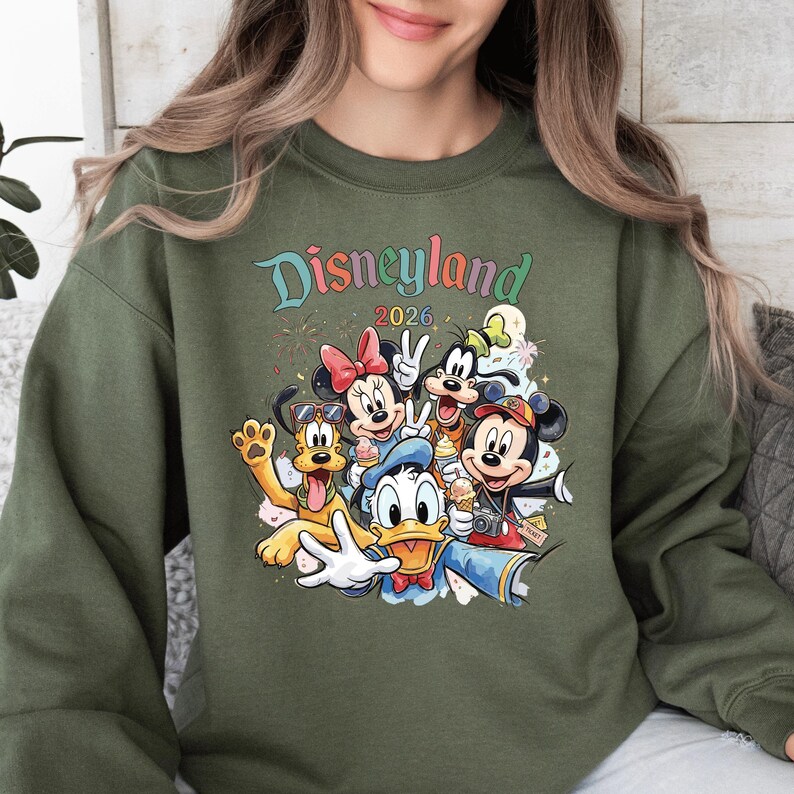A woman wearing a green sweatshirt with a colorful graphic of Disney characters from the theme park.