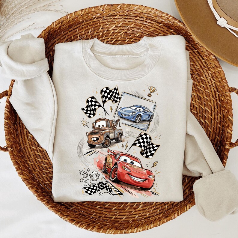 A white t-shirt with a graphic design featuring two cartoon cars, one red and one blue, along with checkered flags and other racing-themed elements.