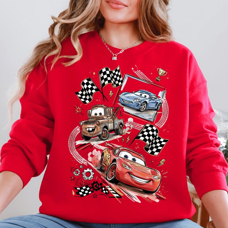 A red sweatshirt with a graphic design featuring cartoon cars and checkered flags, along with other racing-themed elements.