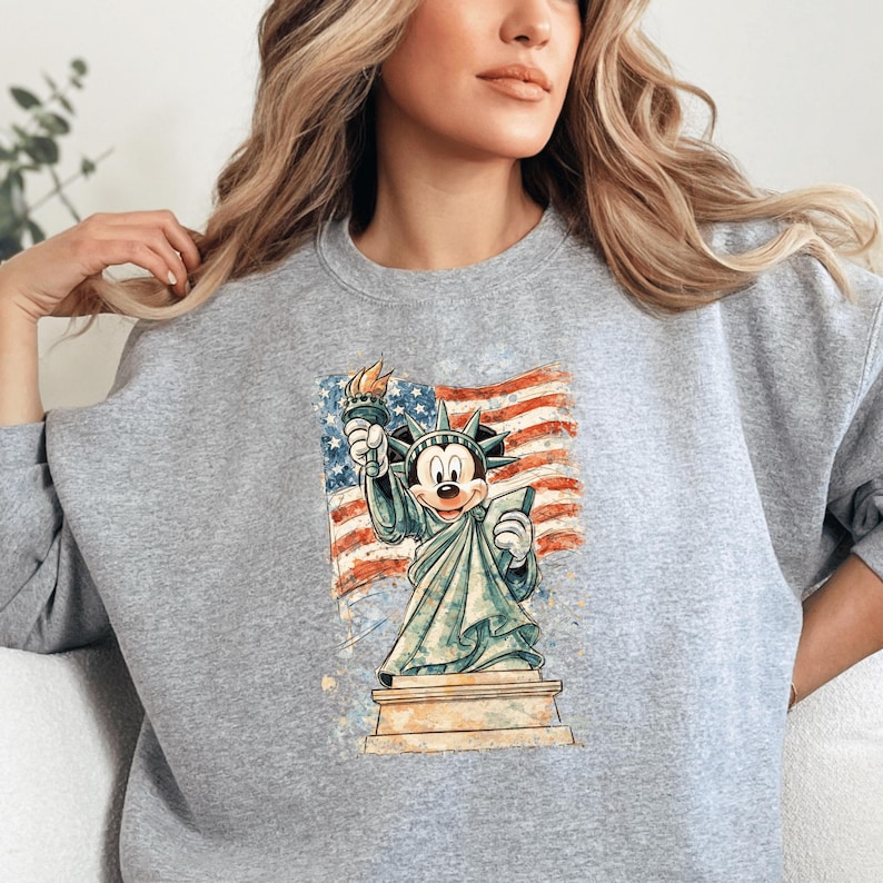 A woman wearing a gray sweatshirt with a graphic of Mickey Mouse in the Statue of Liberty.