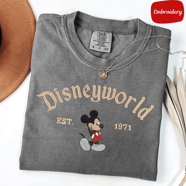 A gray t-shirt with the text "Disneyworld" and a Mickey Mouse graphic, along with the text "EST. 1971" printed on it.