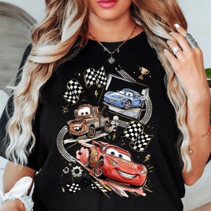 A woman wearing a black t-shirt with a graphic design featuring characters from the animated movie Cars.