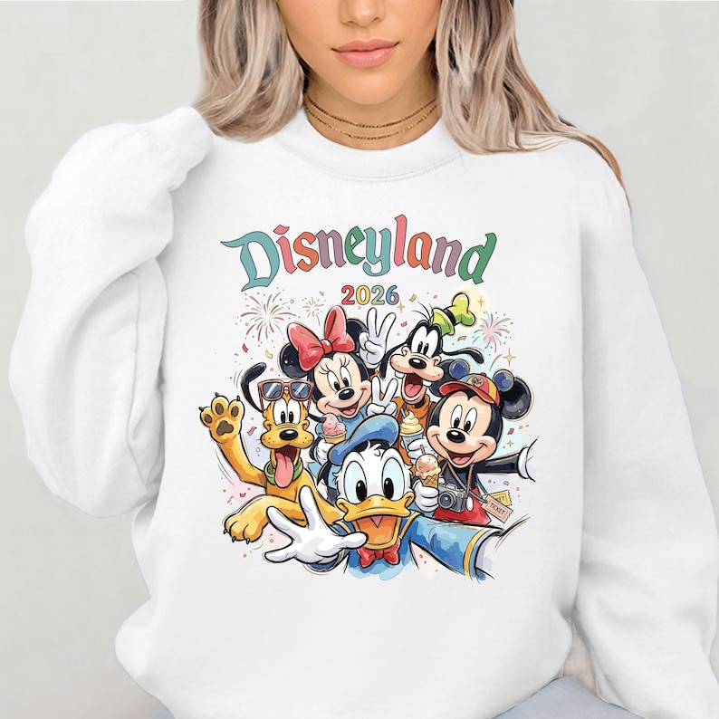 A woman wearing a white sweatshirt with a colorful graphic of Disney characters from the theme park.