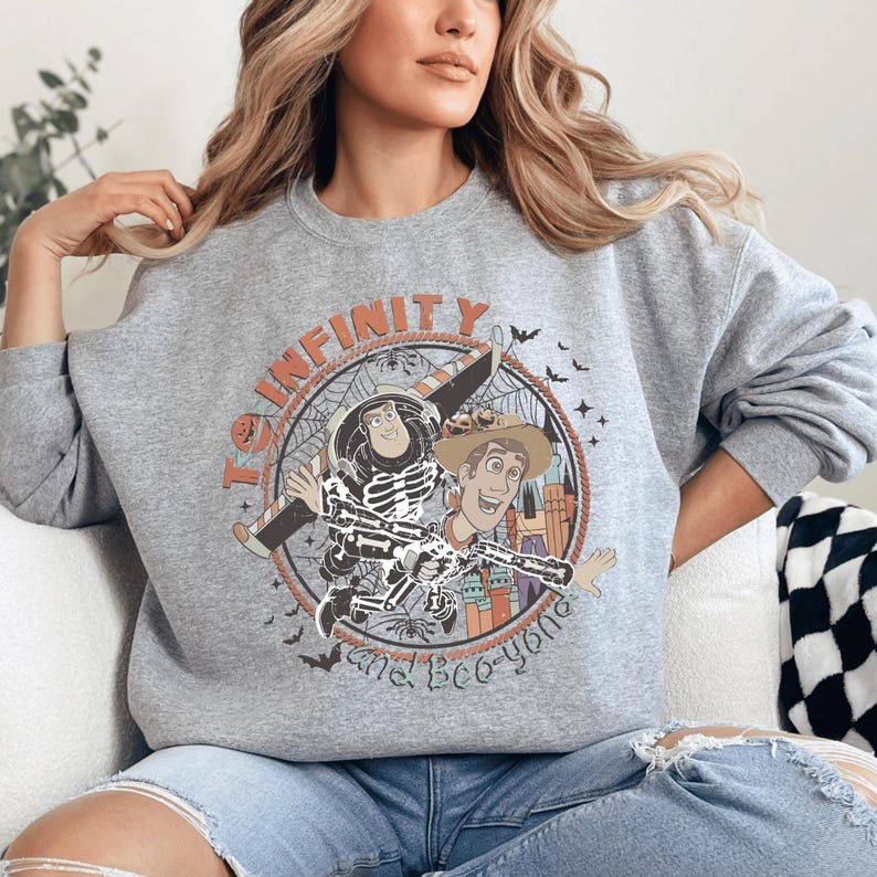 A woman wearing a grey sweatshirt with a graphic design featuring a skeleton and a character from the Toy Story franchise.