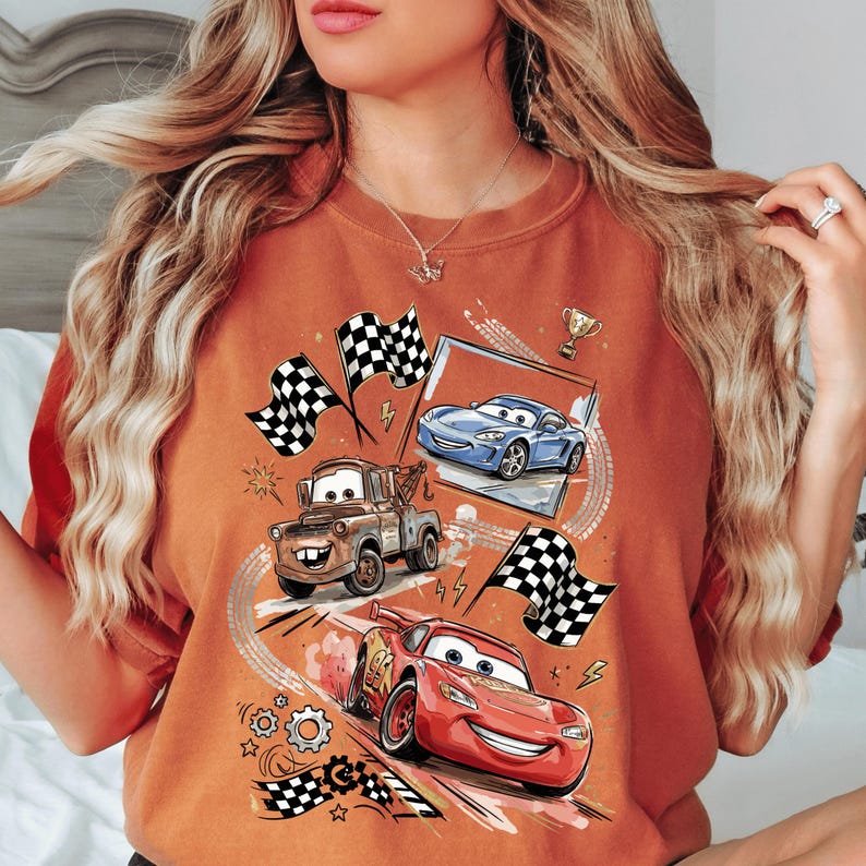 A woman wearing a t-shirt with a graphic design featuring animated cars from the Disney Pixar movie Cars.