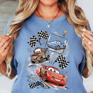 A woman wearing a blue t-shirt with a graphic design featuring animated cars from the Disney Pixar movie Cars.