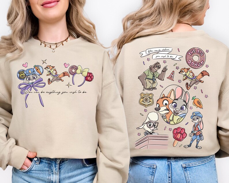 a woman wearing a beige sweatshirt with a colorful cartoon-style design on the front and back.