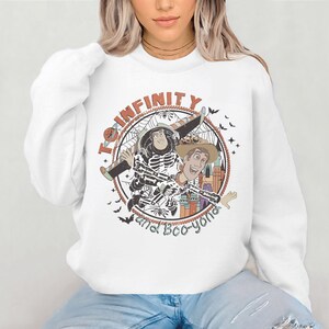 A woman wearing a white sweatshirt with a graphic design featuring characters from the Toy Story franchise.