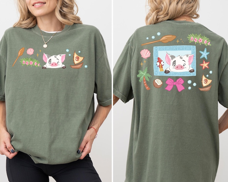A woman wearing a green t-shirt with a cartoon pig design and various colorful elements, including a boat, flowers, and a bow.