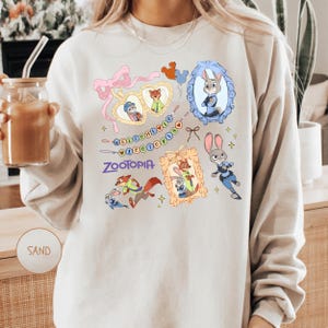 A person wearing a white sweatshirt with a colorful graphic design featuring various cartoon animal characters, including a rabbit, fox, and dog.