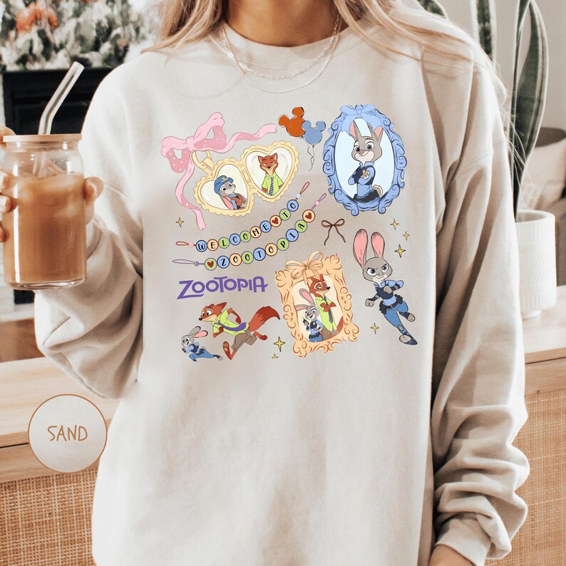 A person wearing a white sweatshirt with a colorful graphic design featuring various cartoon animal characters, including a rabbit, fox, and dog.