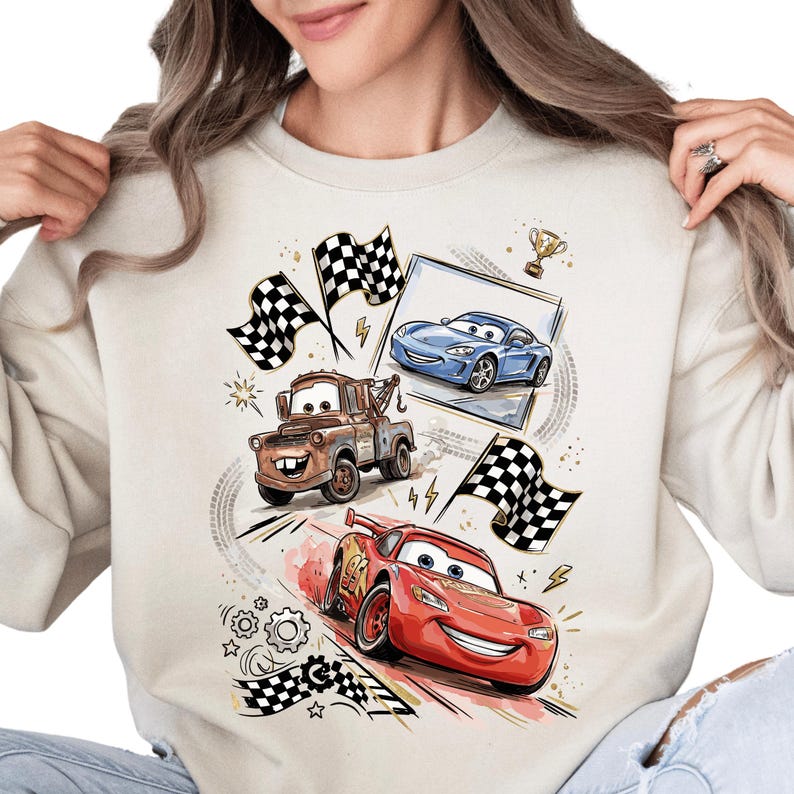 A woman wearing a white sweatshirt with a graphic design featuring cartoon cars and checkered flags.