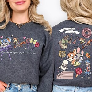 a woman wearing a gray sweatshirt with a colorful and whimsical design on the back.