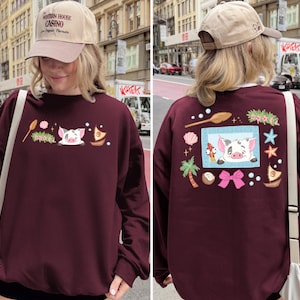 A woman wearing a maroon sweater with a cartoon pig design and various other decorations on the back.