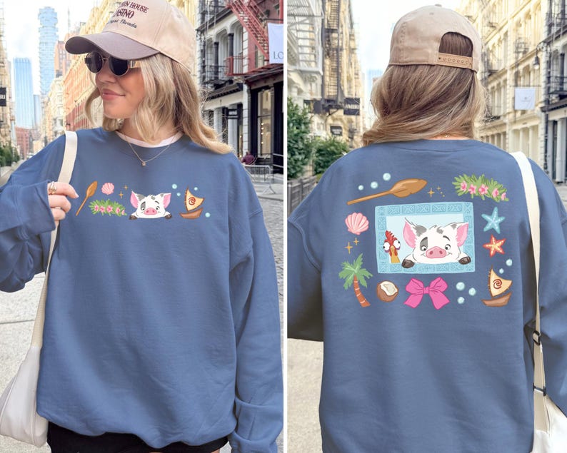 A woman wearing a blue sweatshirt with a cartoon pig design and various colorful illustrations on the back.