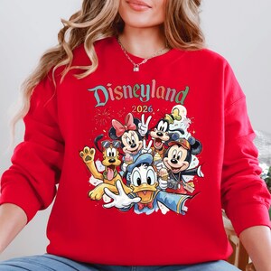 A red sweater with a graphic of Disney characters from the theme park.