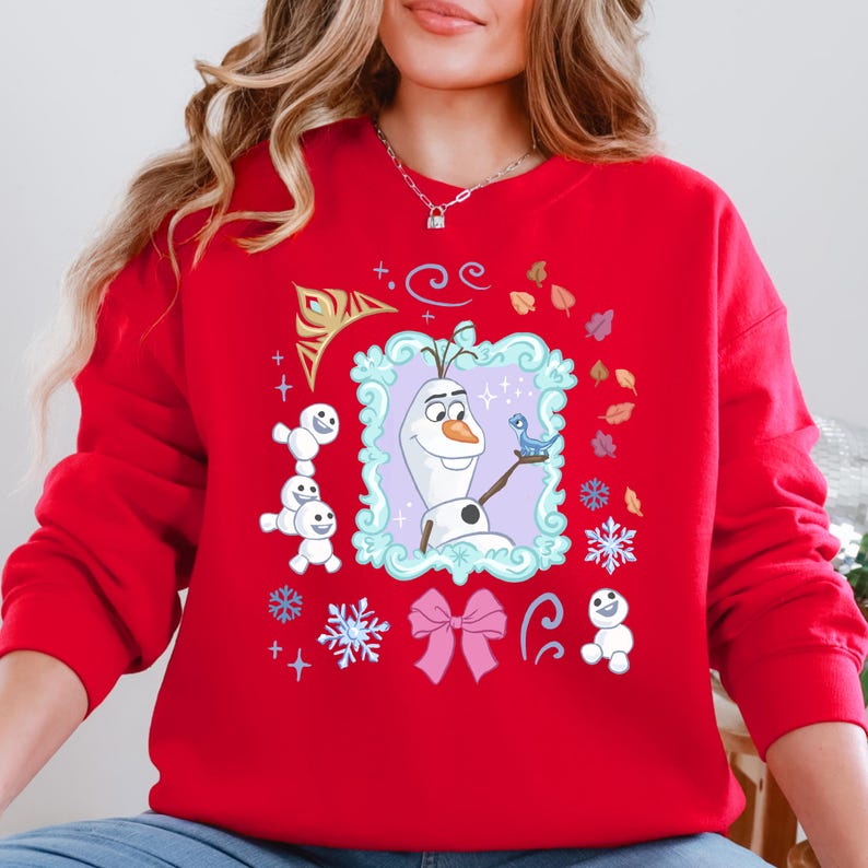 A woman wearing a red sweater with a graphic of Olaf, the main character from the Disney movie Frozen, surrounded by various snow-themed elements.