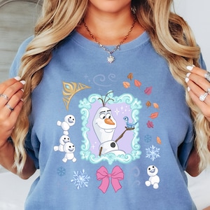 A woman wearing a blue t-shirt with a graphic design featuring characters from the Disney movie Frozen.