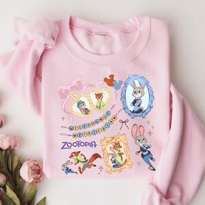 A pink sweatshirt with various cartoon animal characters and a heart-shaped frame design.