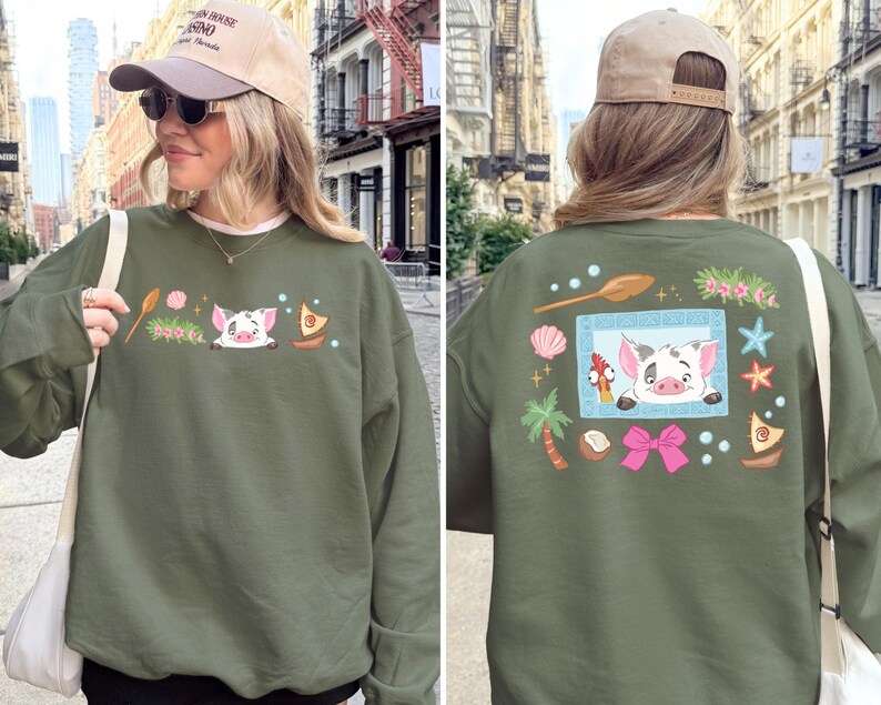 A woman wearing a green sweatshirt with a pig design and various colorful illustrations on the back.