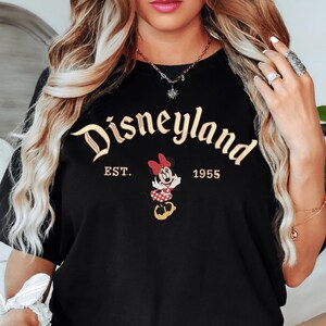 A woman wearing a black t-shirt with the text "Disneyland EST. 1955" and a Minnie Mouse graphic.