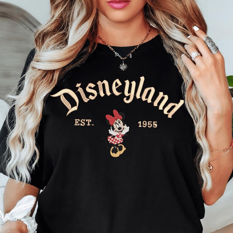 A woman wearing a black t-shirt with the text "Disneyland EST. 1955" and a Minnie Mouse graphic.