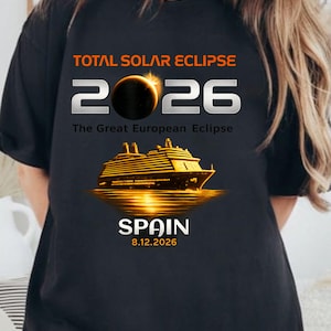 Op de afbeelding: Een zwart t-shirt met de tekst TOTAL SOLAR ECLIPSE 2026, The Great European Eclipse, SPAIN en 12.08.2026. Het ontwerp bevat een afbeelding van een zonsverduistering die de nul in 2026 vervangt en een gouden cruiseschip op het water.