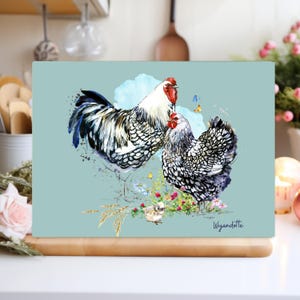 Puede incluir: Una tabla de cortar rectangular con una ilustración de acuarela de dos gallinas Wyandotte, con crestas rojas y plumas negras y blancas. La imagen incluye un pollito, flores y mariposas sobre un fondo azul claro. El texto "Wyandotte" está en la esquina inferior derecha.