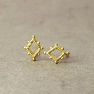 May include: A pair of gold-toned diamond-shaped earrings with a textured surface.