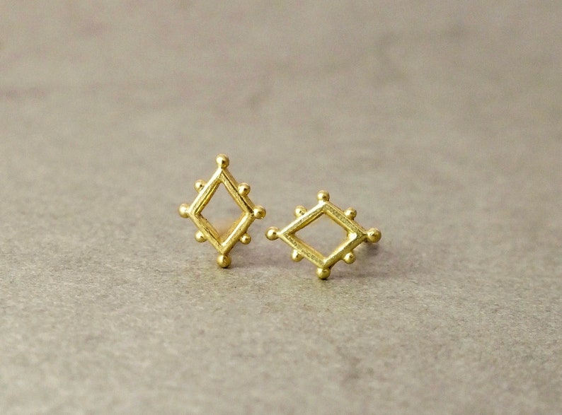 May include: A pair of gold-toned diamond-shaped earrings with a textured surface.